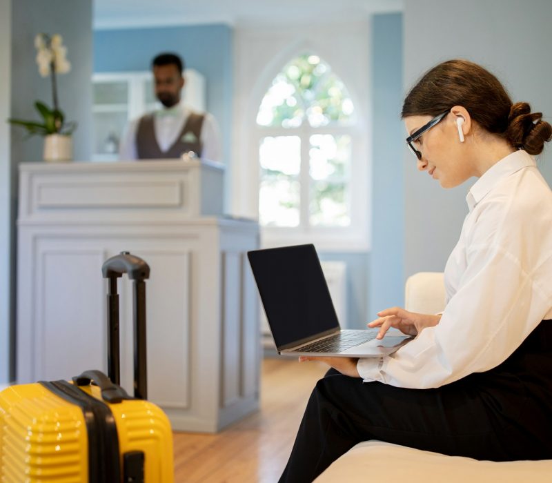 Business Lady Using Laptop Wearing Earbuds Working Online At Hotel